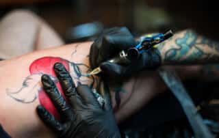 patron getting a colorful tattoo in a shop in augusta maine