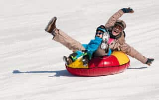 woman and child snow tubing on a mountain in Maine